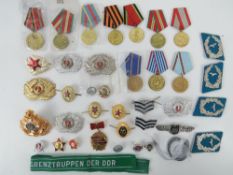 A quantity of assorted Russian and DDR badges and medals, approx 39 items.