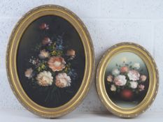 Two mid 20thC oil on canvas floral still life paintings in matched oval frames,