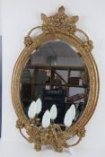 A good early 20thC oval gilt wall mirror having triple sconce under and wired for electricity.