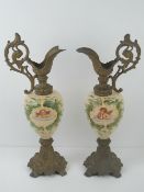A pair of decorative ceramic 'ewers' having transfer printed cherubs upon and further hand painted
