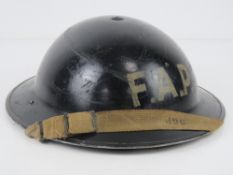 A WWII Brodie helmet FAP (First Aid Post) with liner and chin strap.