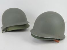 Two US helmets (rear seam) with liners and chin straps.