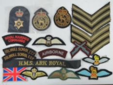 A quantity of assorted British cloth titles, rank titles, shoulder badges and cap badges (17 items).