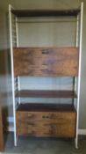 A c1960s walnut wall unit comprising various shelves and fall front cupboards, 93 x 36 x 200cm.