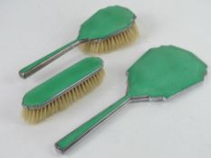 An Art Deco dressing table set having green guilloche enamel back comprising hairbrush,
