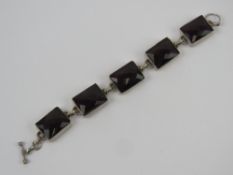A five panel bracelet each set with faceted garnet coloured paste, no apparent hallmarks,