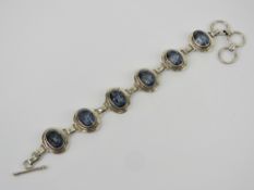 A silver and tanzanite bracelet, six oval cut tanzanites each set in single panel, 2cm wide,