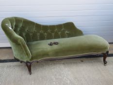 An Edwardian button back chaise lounge raised over shaped and scrolled legs.
