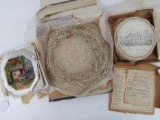 A quantity of handmade lace doilies together with a boxed set of vintage doilies showing houses of