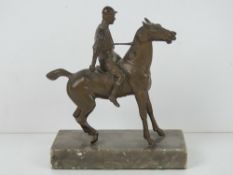 A cold cast bronze sculpture of jockey on horseback raised over marble base, 12cm wide,