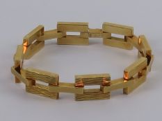 An 18ct gold geometric articulated panel bracelet having bark effect and poloshed rectangular links,