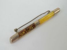 A white metal bar brooch having inset Baltic and egg yolk amber, no apparent hallmarks,