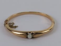 A 15ct gold hinged bangle having 'patent bolt snap', stone having been replaced with plastic bead,