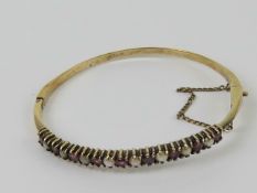 A vintage ruby and split pearl bangle, no apparent hallmarks possibly gold on silver, approx 5.