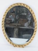 An oval bevel edged wall mirror in conte