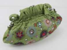 A lime green fabric handbag having embroidered pattern upon.