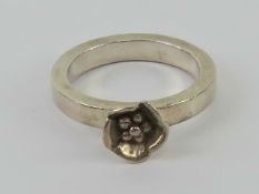 A silver floral ring, single flower on c