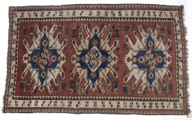 Star Kazak style red ground rug with three central medallions and panel border, 223cm x 139cm
