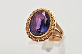 A CONTINENTAL RING SET WITH A SYNTHETIC COLOUR CHANGE OVAL CORRUNDUM. Rope twist surround to split