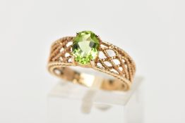 A 9CT GOLD PERIDOT RING, the oval peridot in a four claw setting to the tapered openwork rope