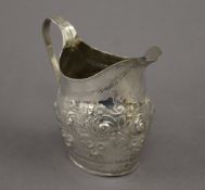 An embossed Georgian silver cream jug. 9.5 cm high. 2.7 troy ounces.
