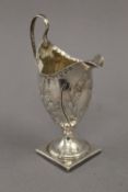 An embossed Georgian silver cream jug. 13.5 cm high. 2.1 troy ounces.
