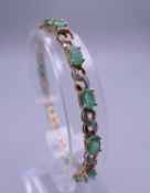 A 9 ct gold diamond and emerald bracelet. 18.5 cm long. 8.6 grammes total weight.