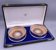 A cased pair of silver coasters. Each 12.5 cm diameter.
