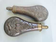 Two copper and brass powder flasks, both with embossed decoration, largest 20cm long.