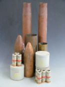 Four large brass shell cases with two nose cones and three tins of Anti-Riot CS baton rounds, all