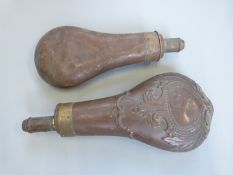 Two copper and brass powder flasks, one with embossed decoration, largest 20.5cm long.