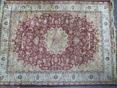 Persian carpet / rug with central flower head and further floral decoration on a red ground with