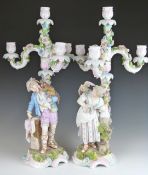 A pair of 19thC German figural candelabra, one with a monkey on the shoulder of a male figure, the