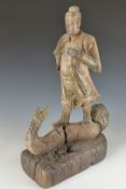 A wooden carved Chinese figure of a robed Chinese man astride a two headed serpent, probably 18thC