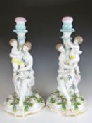 A pair of German porcelain figural candlesticks emblematic of motherhood, with painted and applied