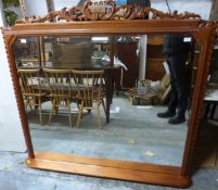 A mahogany overmantel mirror with bevelled glass, integral shelf and removable ornate finial,
