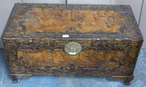 Chinese heavily carved camphor wood trunk with engraved brass lock raised on carved bracket feet,