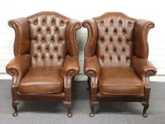 A pair of faux leather wing back Chesterfield armchairs, H107 x W84cm