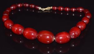 A cherry amber necklace made up of 22 graduated oval beads, 59g, largest bead 3 x 2.1cm