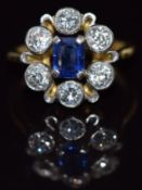 An 18ct gold ring set with an emerald cut sapphire of approximately 0.4ct surrounded by diamonds,
