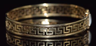 A 9ct gold bangle with pierced Greek key decoration, 15.9g