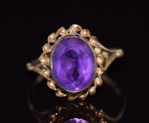 A 9ct gold ring set with an oval cut amethyst with a twisted border, 1.9g, size K