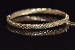 A 9ct gold bangle with twisted ridged design 8.9g