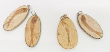 Four fossilised fish pendants