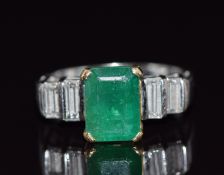 An 18ct white gold ring set with an emerald cut emerald and four baguette cut diamonds, total