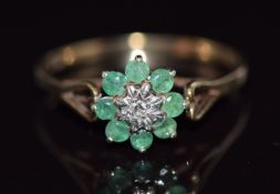 A 9ct gold ring set with a diamond surrounded by emeralds, 1.3g, size M