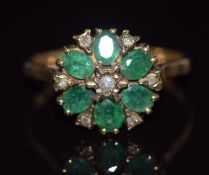 A 9ct gold ring set with round cut diamonds and oval cut emeralds in a cluster, 2.1g, size M