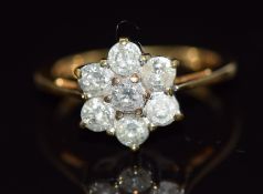 An 18ct gold ring set with seven round cut diamonds in a flower cluster, total diamond weight