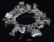 A silver charm bracelet with over 20 charms including boat, St Christopher, car, etc, 103g