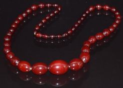 A cherry amber necklace made up of 53 graduated oval beads, 64g, largest bead 2.1 x 3cm